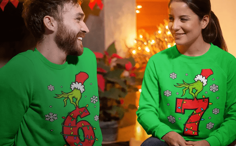 Two people wearing coordinated holiday sweatshirts